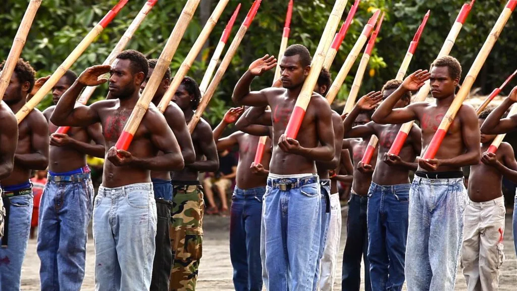 this image shows the men of a remote tribe imitating soldiers in WWII called the cargo cult